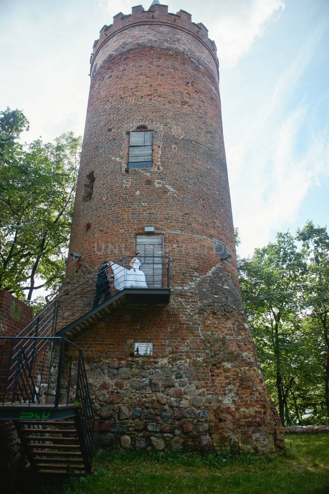 Bride and groom at a photo session in the nature. Old castle tower