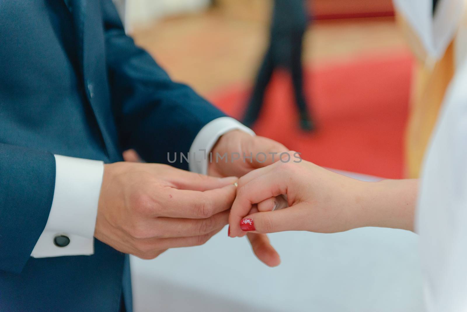the bride and groom during the wedding ceremony put wedding rings on their fingers.