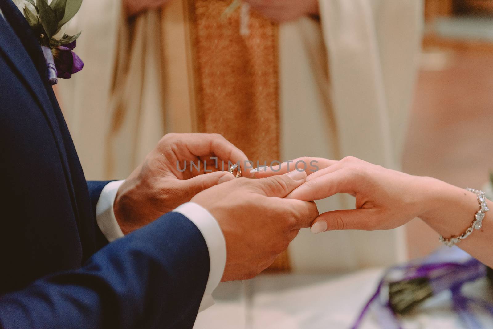 the bride and groom during the wedding ceremony put wedding rings on their fingers.