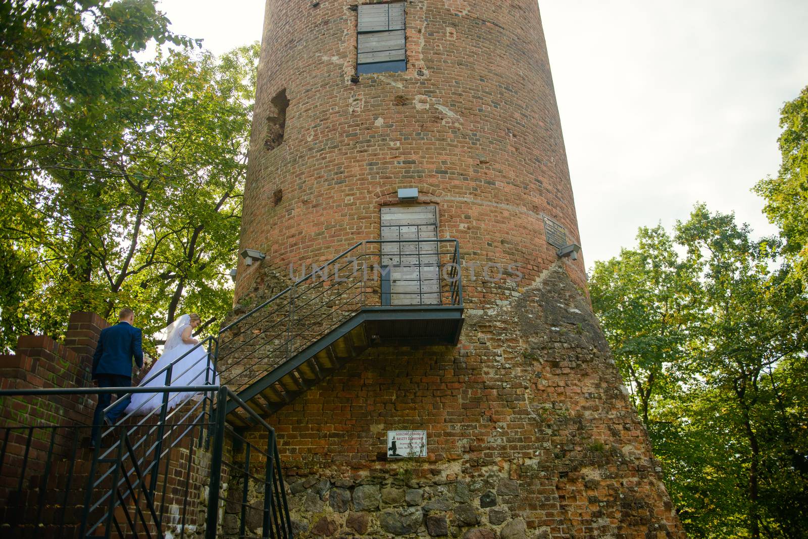 Bride and groom at a photo session in the nature. Old castle tower