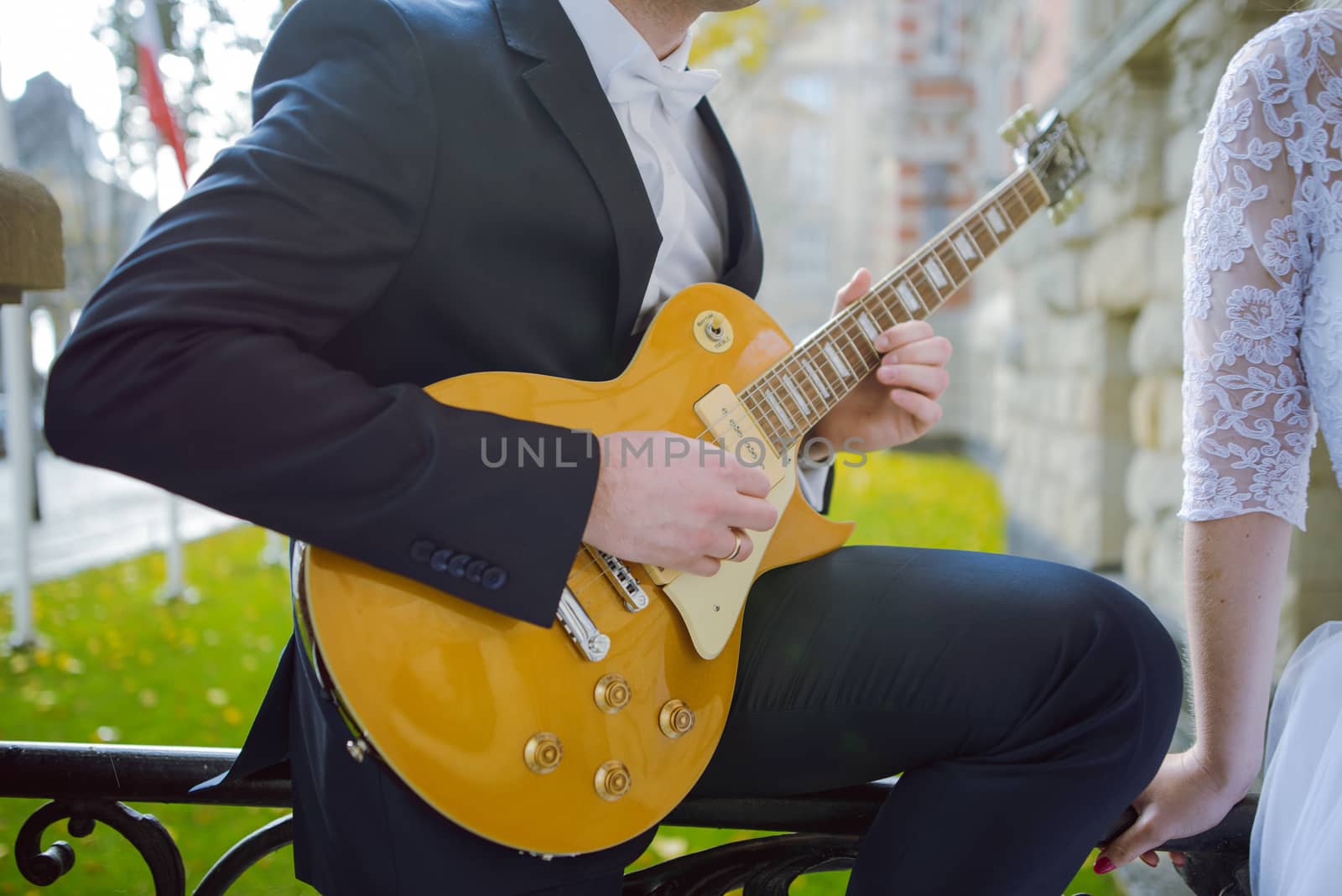 Bride and groom at a photo session in the nature. Groom plays guitar.