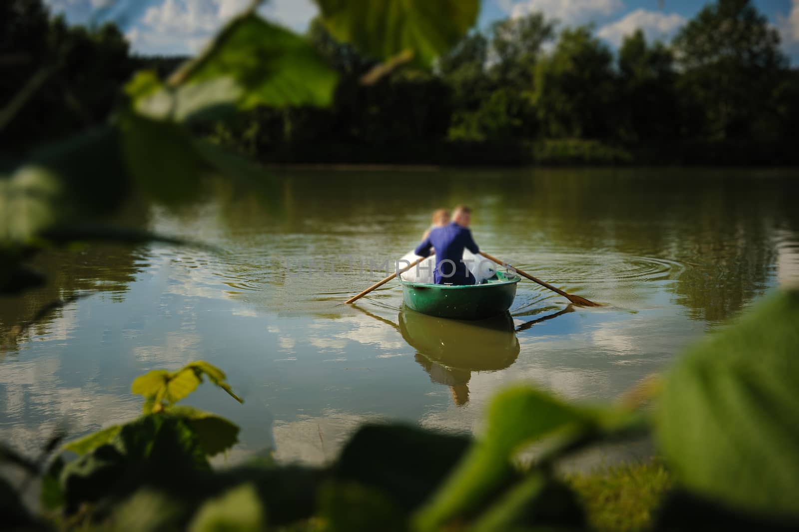 Bride and groom at a photo session in the nature. Newlyweds in the boat on the lake