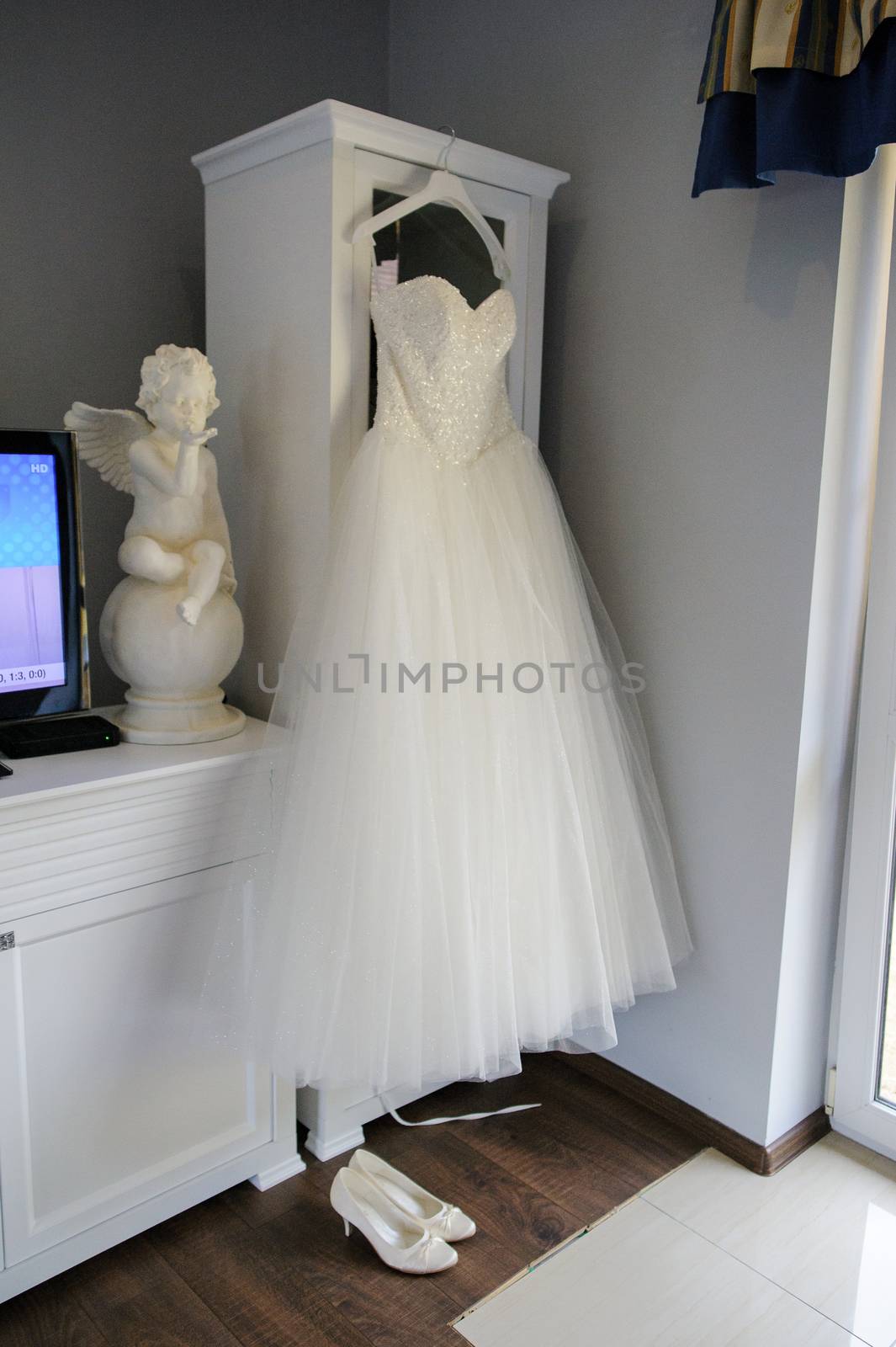 Bridesmaid helping slender bride lacing her wedding white dress, buttoning on delicate lace pattern with fluffy skirt on waist. Morning bridal preparation details newlyweds. Wedding day moments, wear.