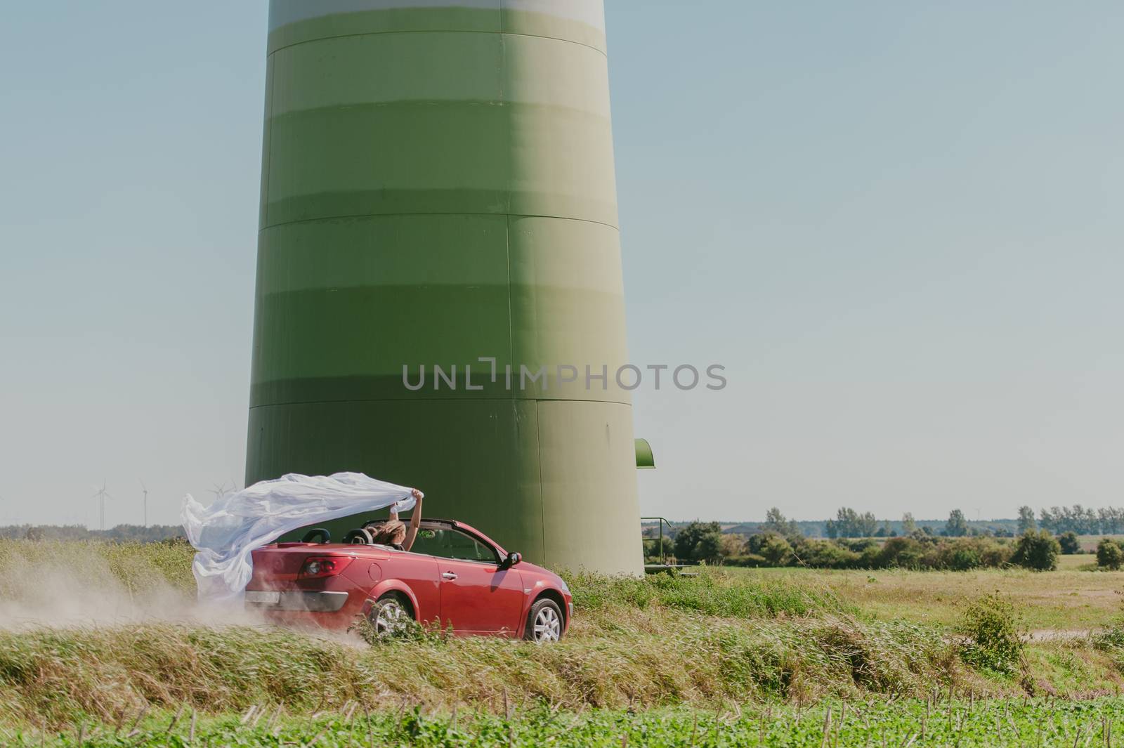 Bride and groom at a photo session in the nature. Moving fast red car with veil outside