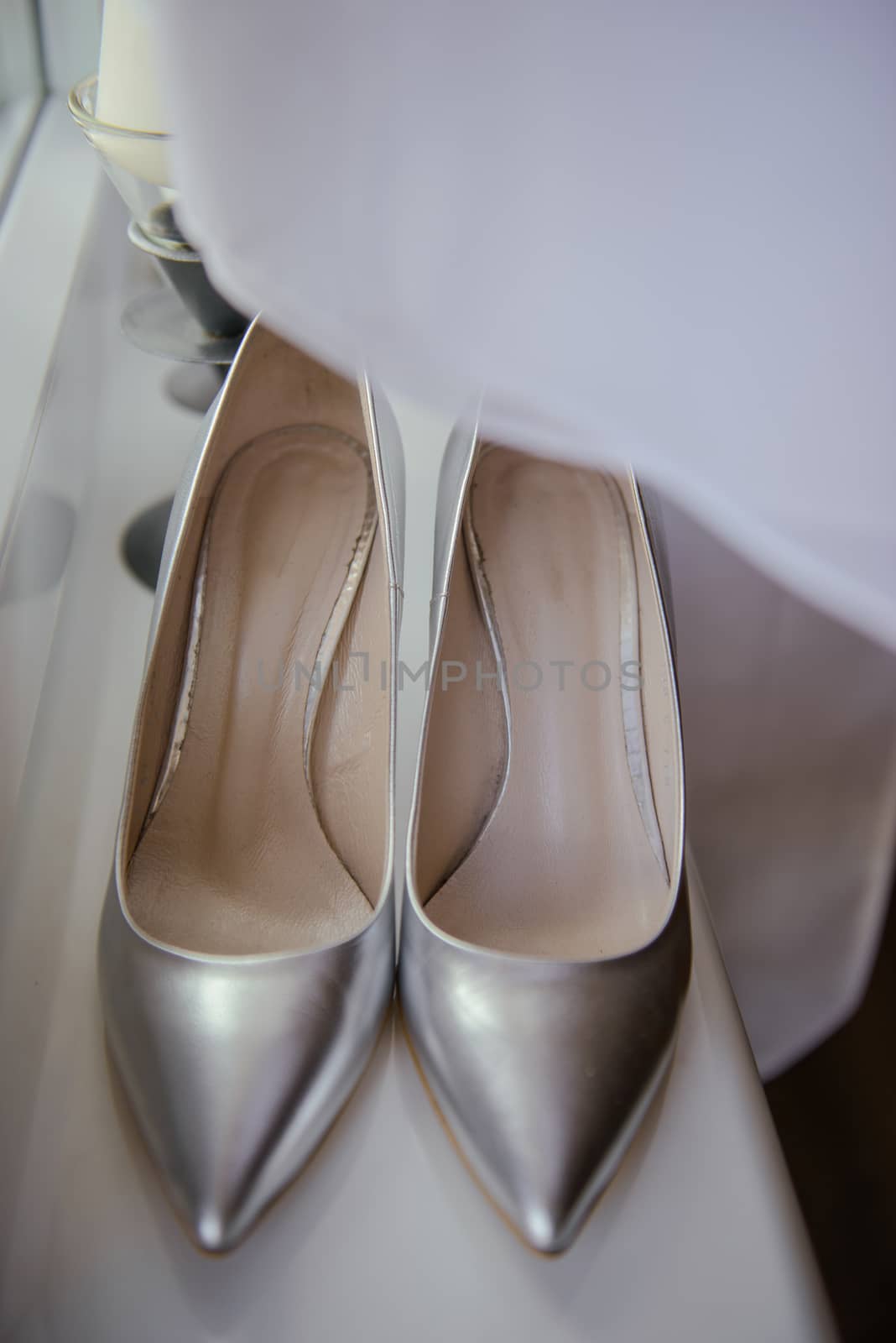 The bride shows white wedding shoes. Wedding detail. Close up