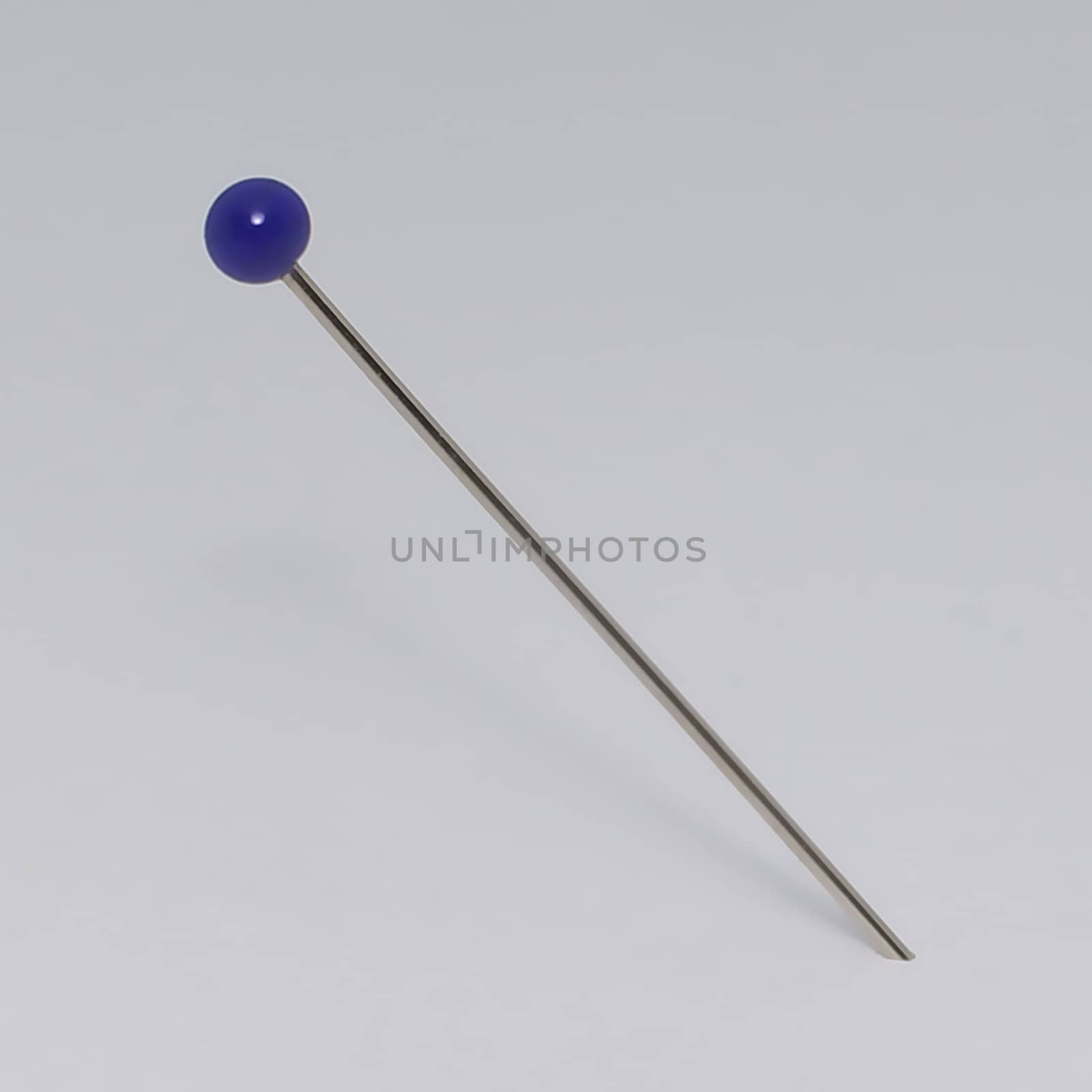 A close up of a single blue pin in a sheet of paper