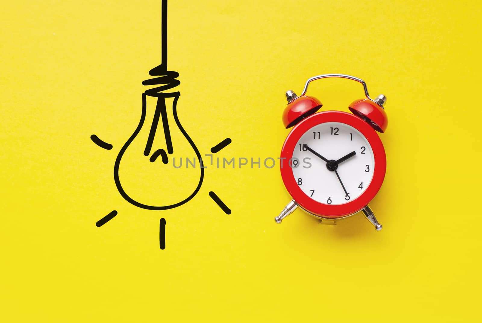 Alarm clock with hand drawn light bulb on vivid yellow paper in a concept of innovation and start-ups