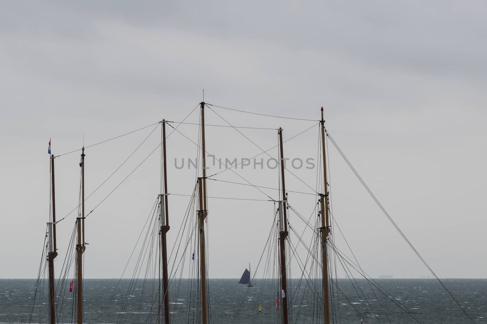 Sailboat in the Wadden Sea as seen through the masts of two three-masted sailboats
