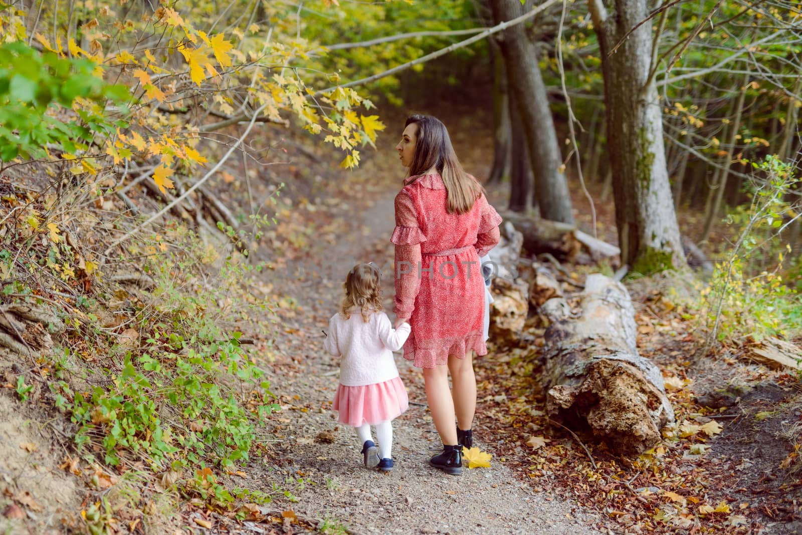 Mother holds daughter in her arms in the park on a sunny day. Autumn day