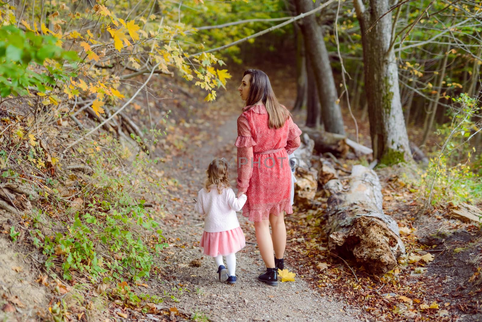 Mother holds daughter in her arms in the park on a sunny day. Autumn day