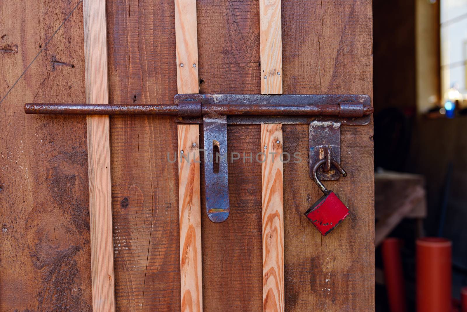 Old red padlock on a wooden door