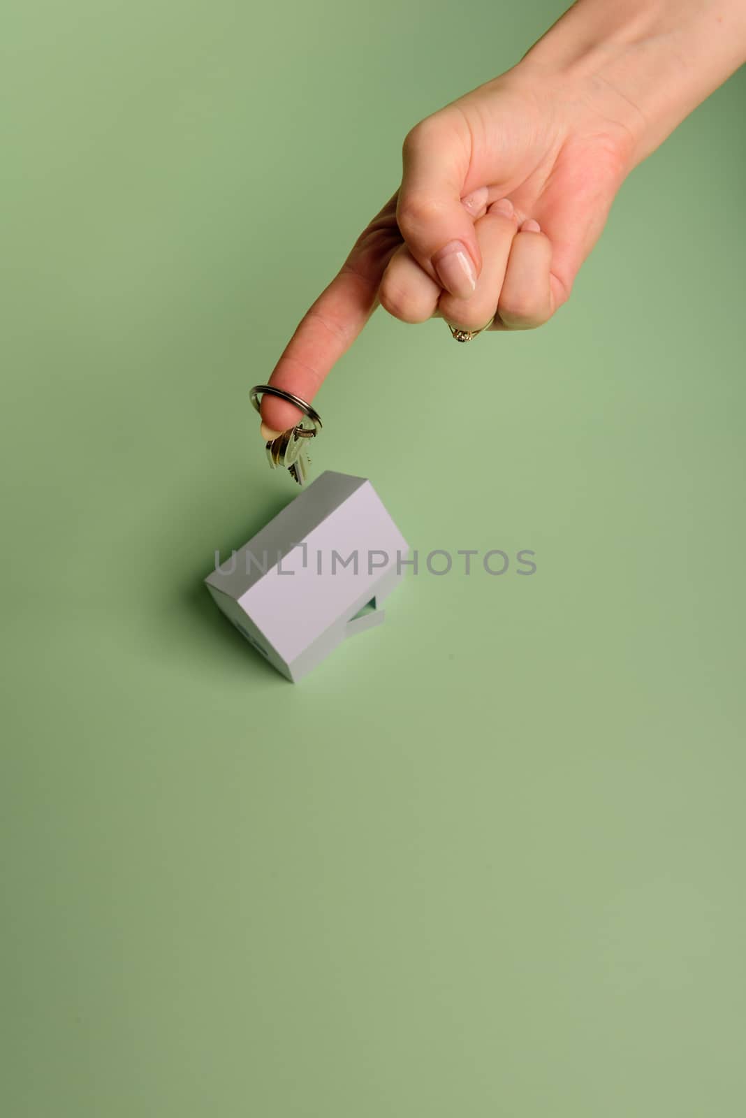 White family paper house. House keys in hand on mint background paper. Minimalistic and simple concept, style. Copy space. Vertical orientation. Family moving or removal concept.