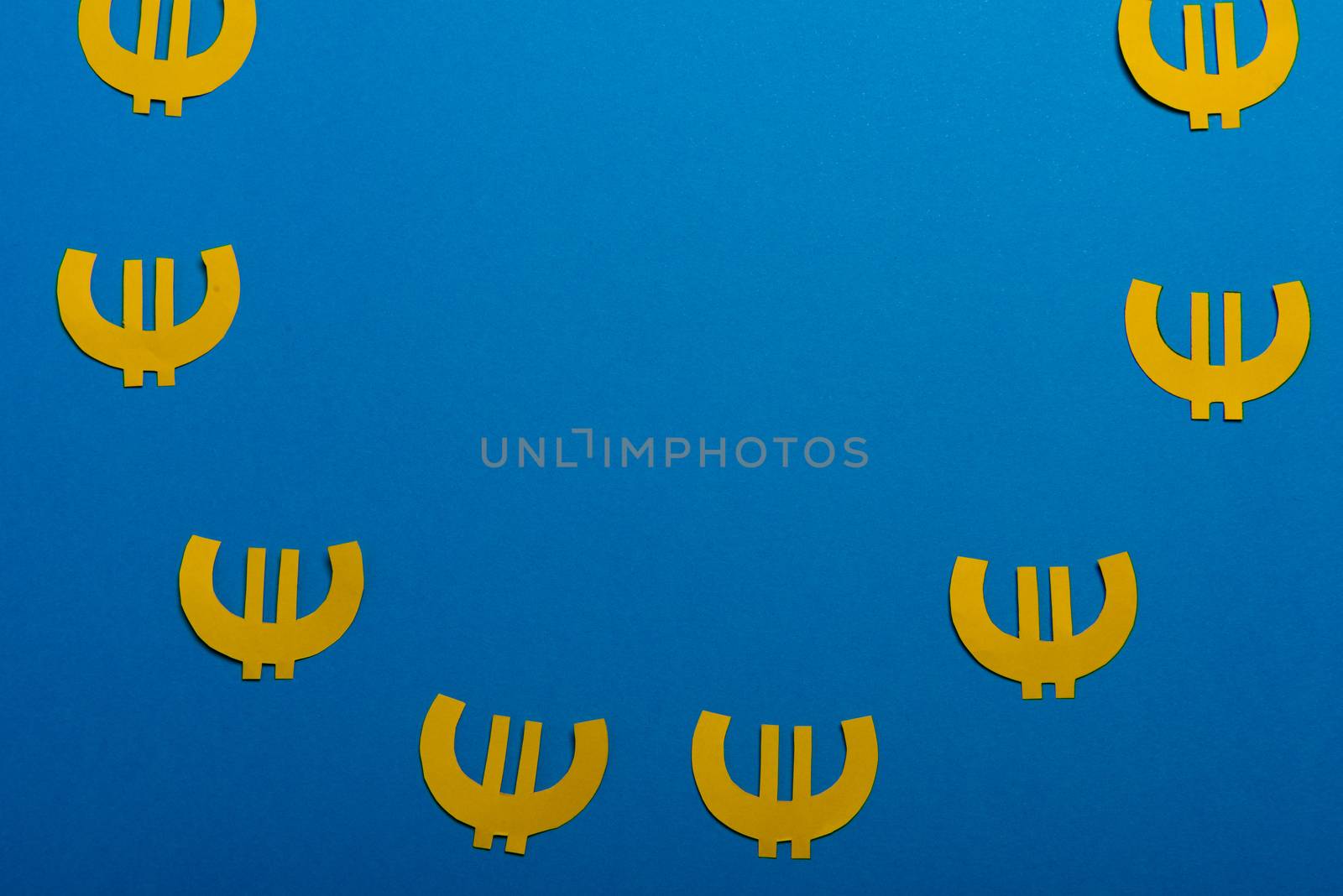 Paper yellow symbols of euro currency on blue background. View from above with copy space