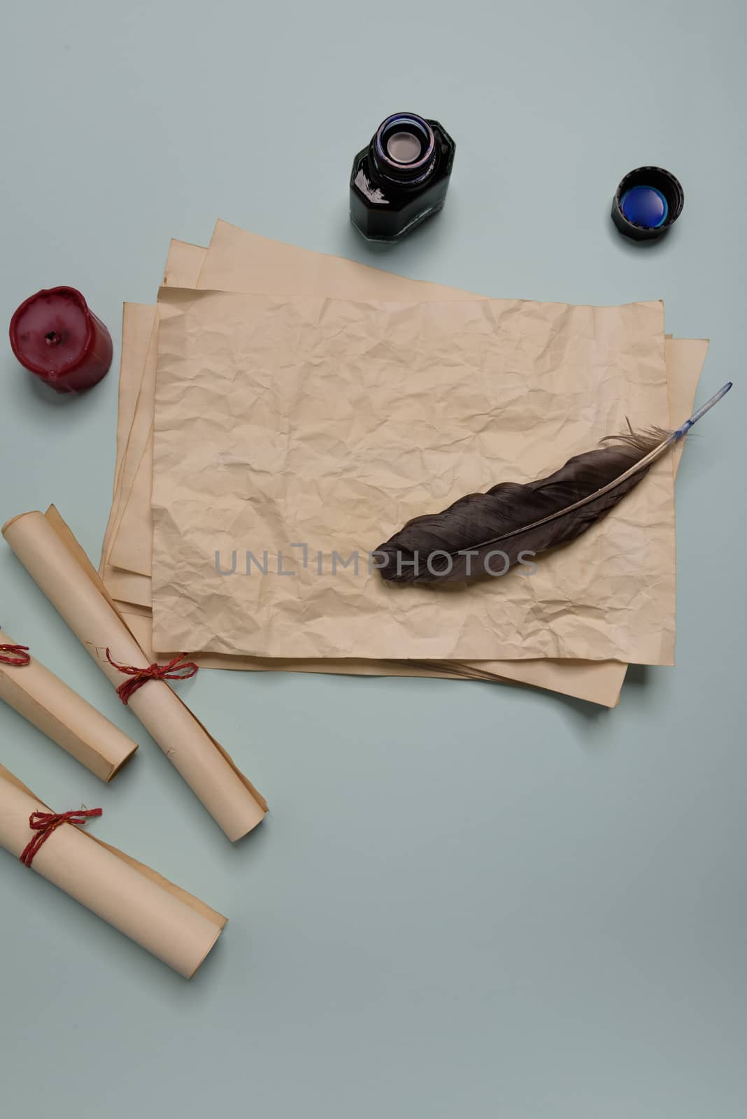 Raven feather, inkwell and old yellowed paper on red background. Copy space. Old letter.