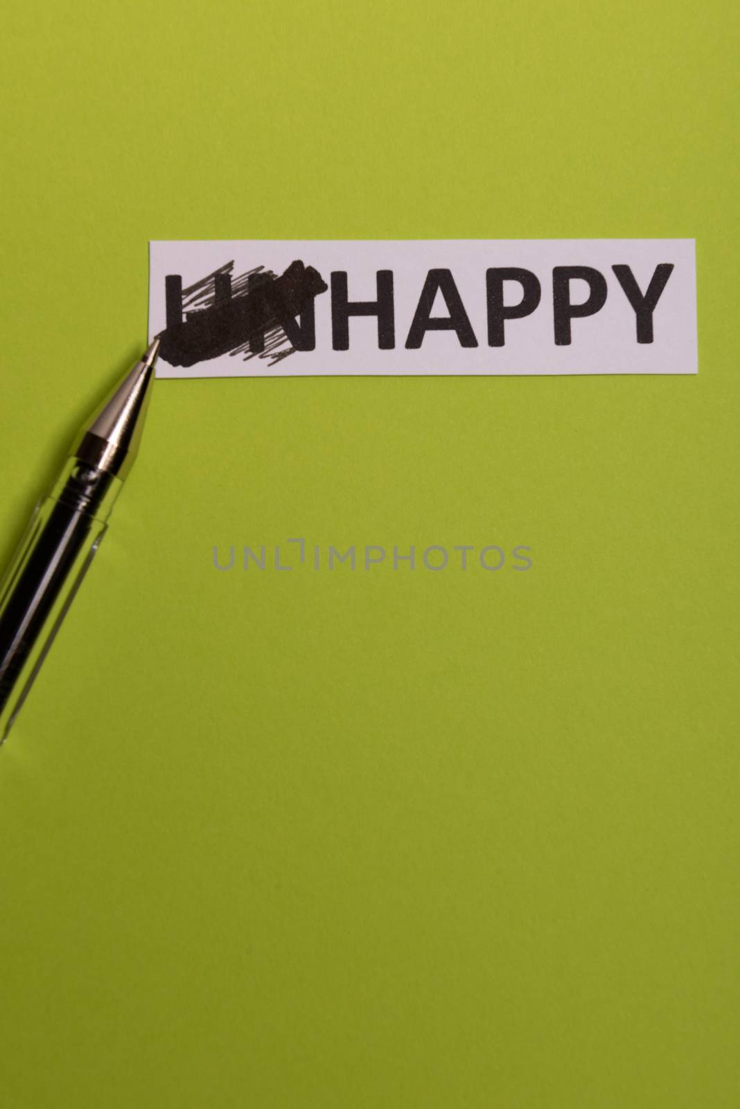 card with text unhappy, cutting word 'un' so it written 'happy'. Copy space. Lime background. Studio shoot.
