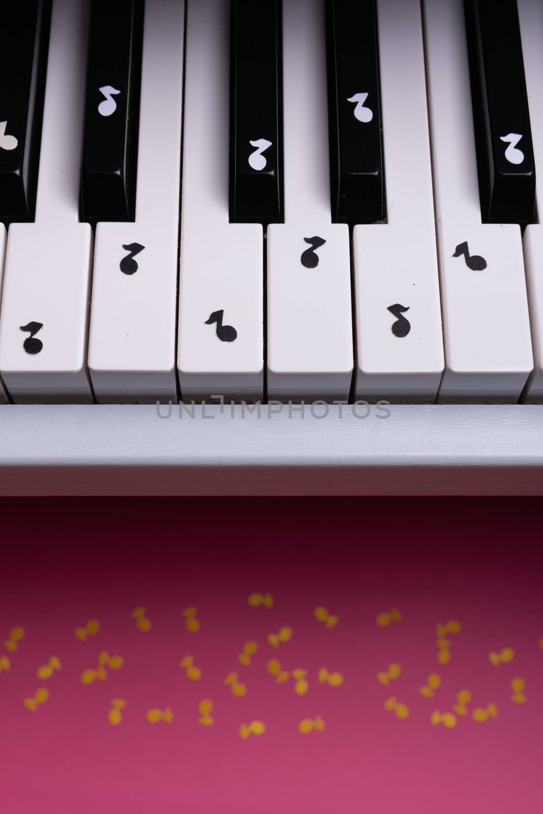 white toy piano with paper notes. music piano concept. view from above. White, black and yellow music notes.