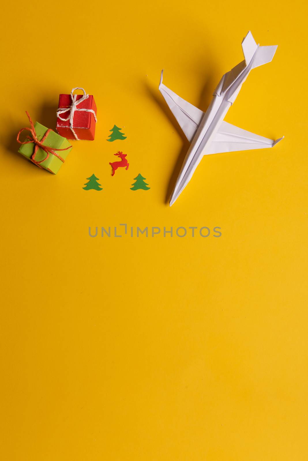Group of paper plane in one direction and with one individual pointing in the different way on yellow background. Christmas ttrip. Presents and gifts