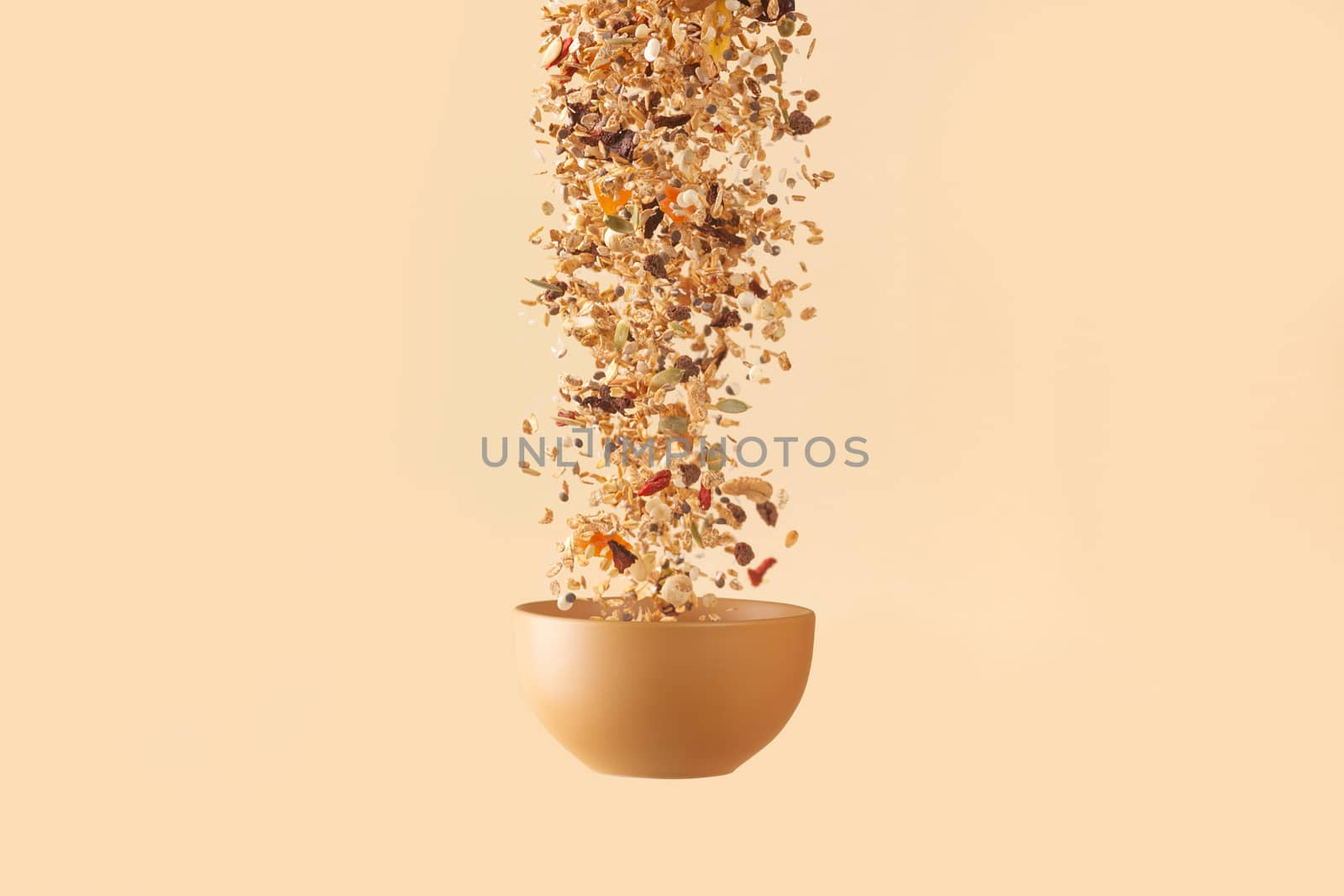 Falling granola with candied fruits and nuts  to baige flying bowl on baige background. Stock photo of nutritient food. Conceptual photo of vegan and vegetarian healthy food.