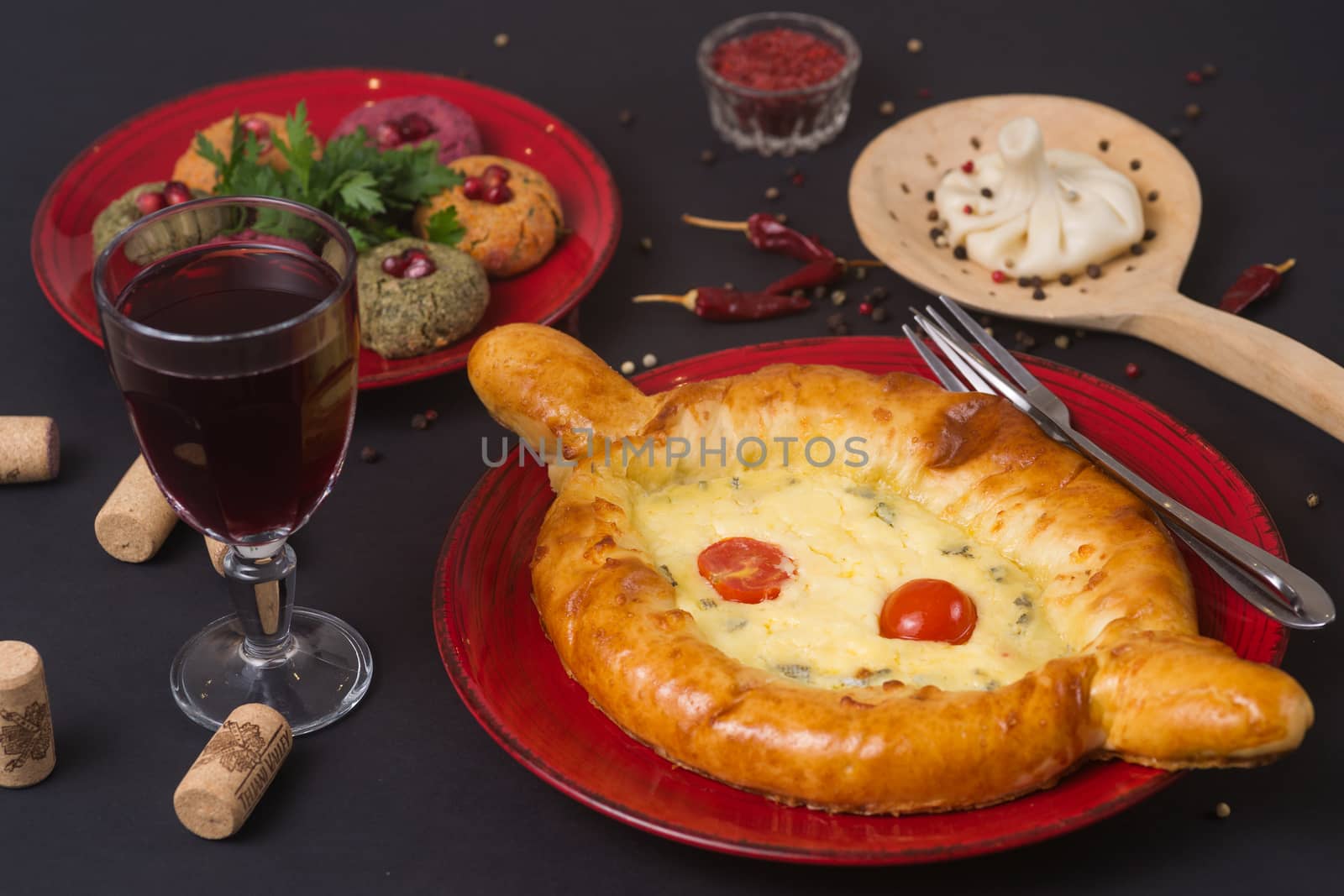 Georgian food on black table. khinkali, phali,  khachapuri with tomatos, adjika and a glass of wine.