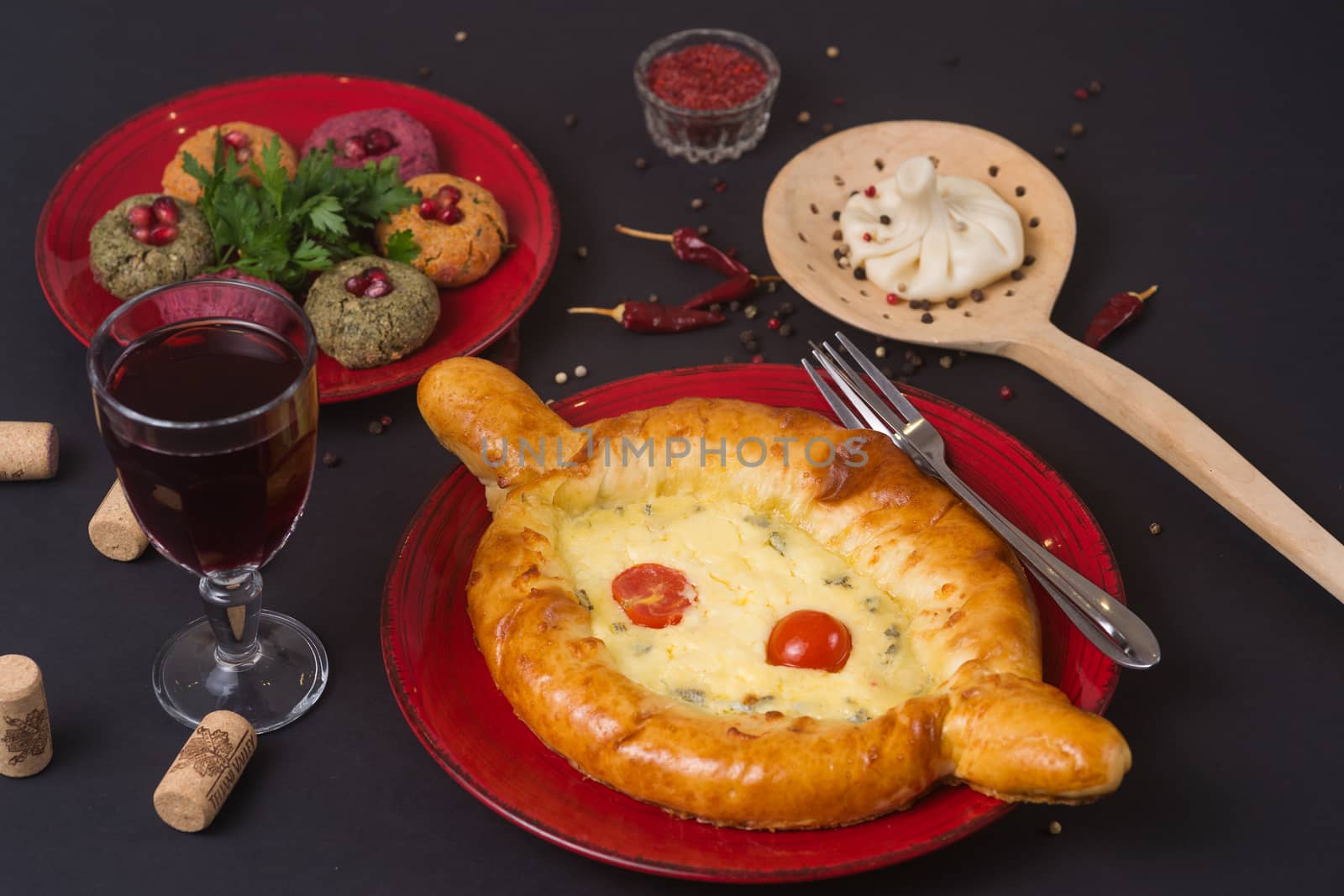 Georgian food on black table. khinkali, phali,  khachapuri with tomatos, adjika and a glass of wine.