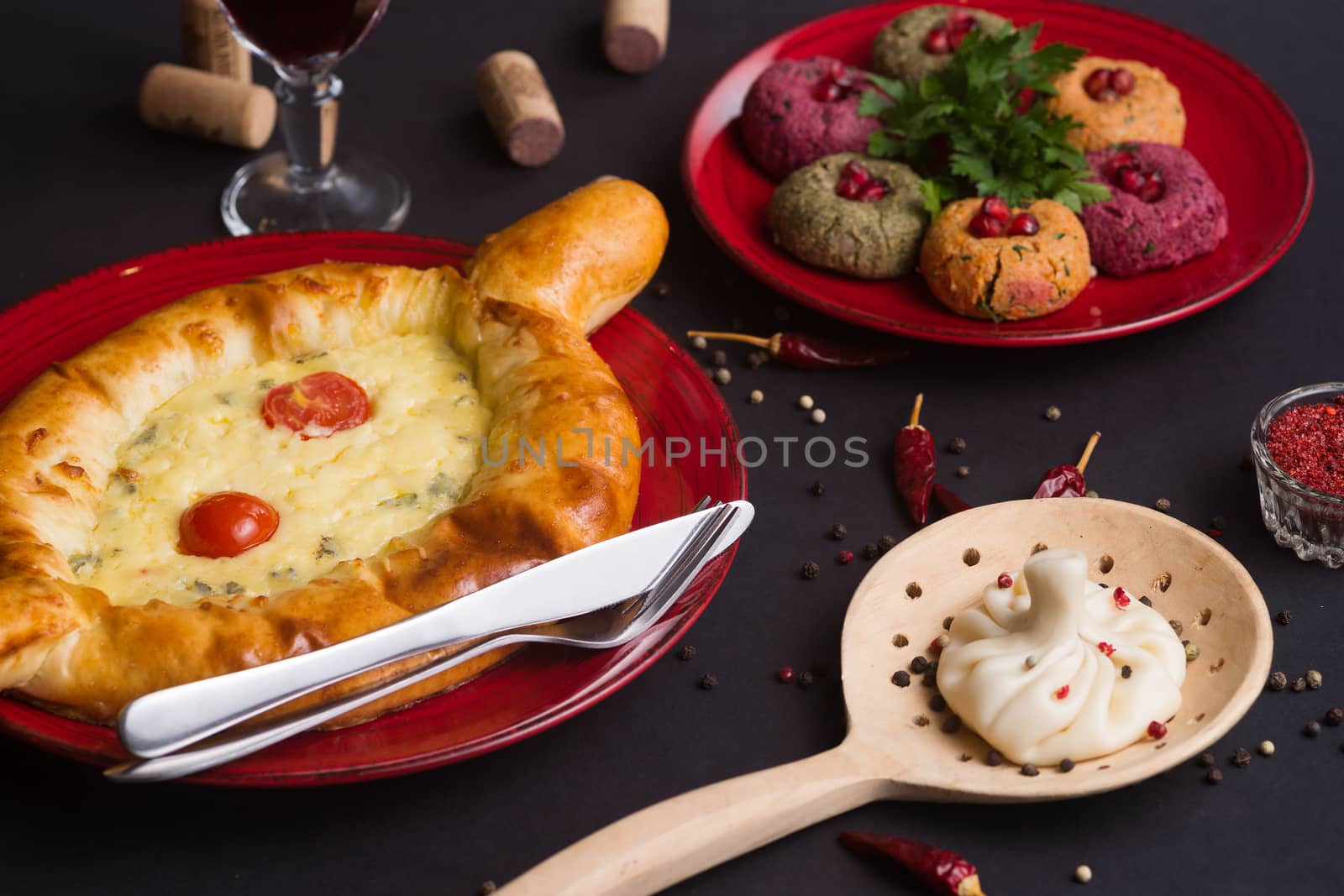 Georgian food on black table. khinkali, phali,  khachapuri with tomatos, adjika and a glass of wine.