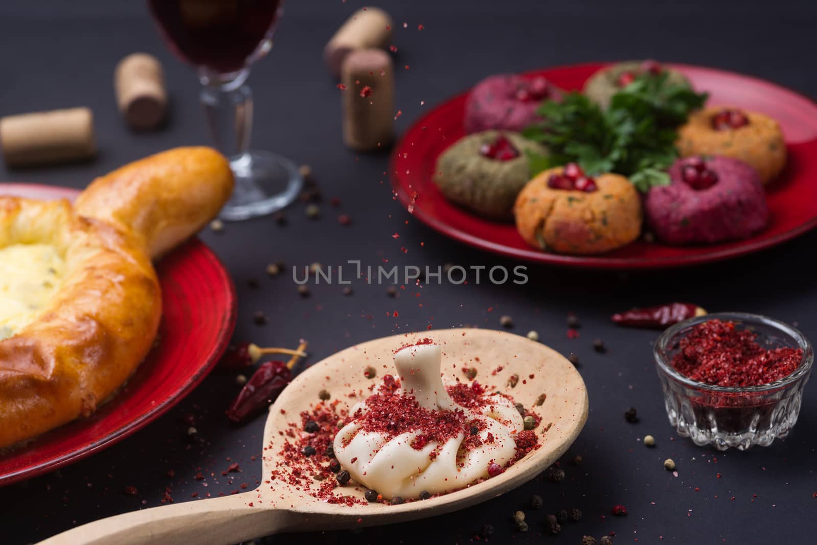 Georgian food on black table. khinkali, phali,  khachapuri with tomatos, adjika and a glass of wine.