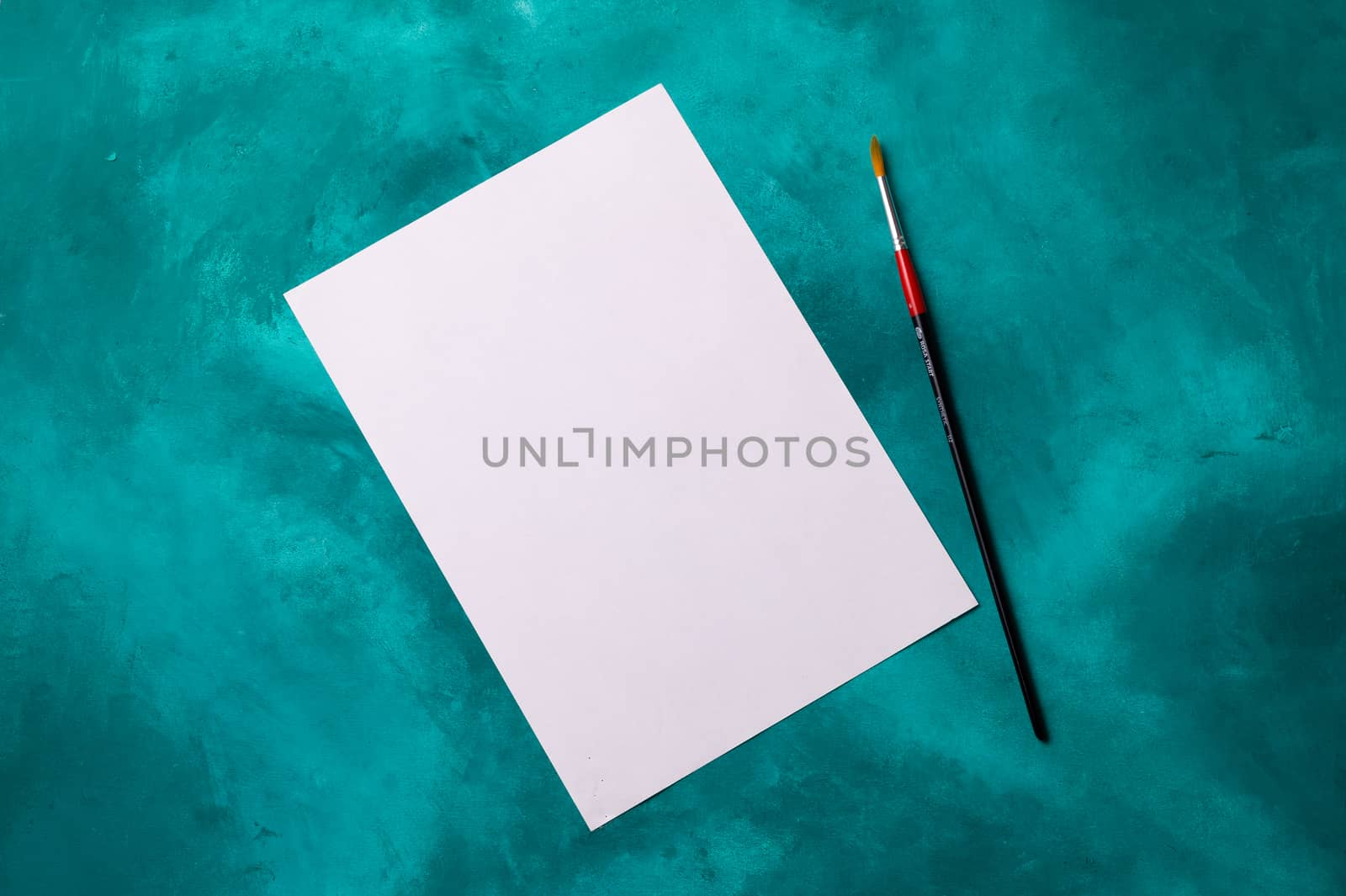 Clear white paper sheet with brush lies on turquoise background. Perfect mockup for any signs or motivation list.