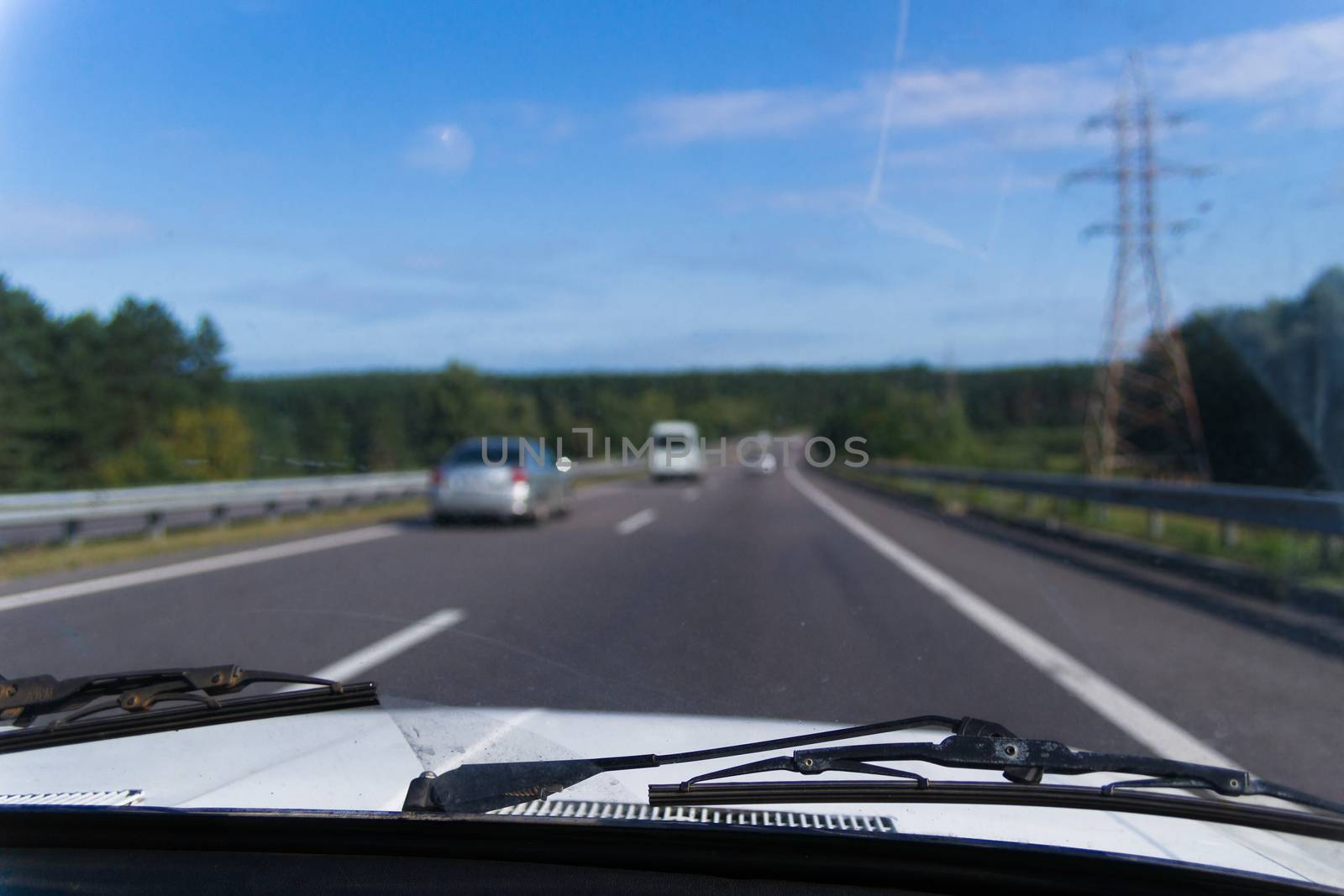 View of a passenger from the passenger compartment on the highway. A fine sunny day and almost free road. 