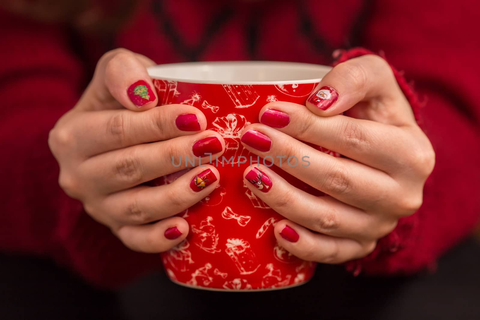 Woman's hand holding a red cup of coffee. With a beautiful winter manicure. Drink, fashion, morning