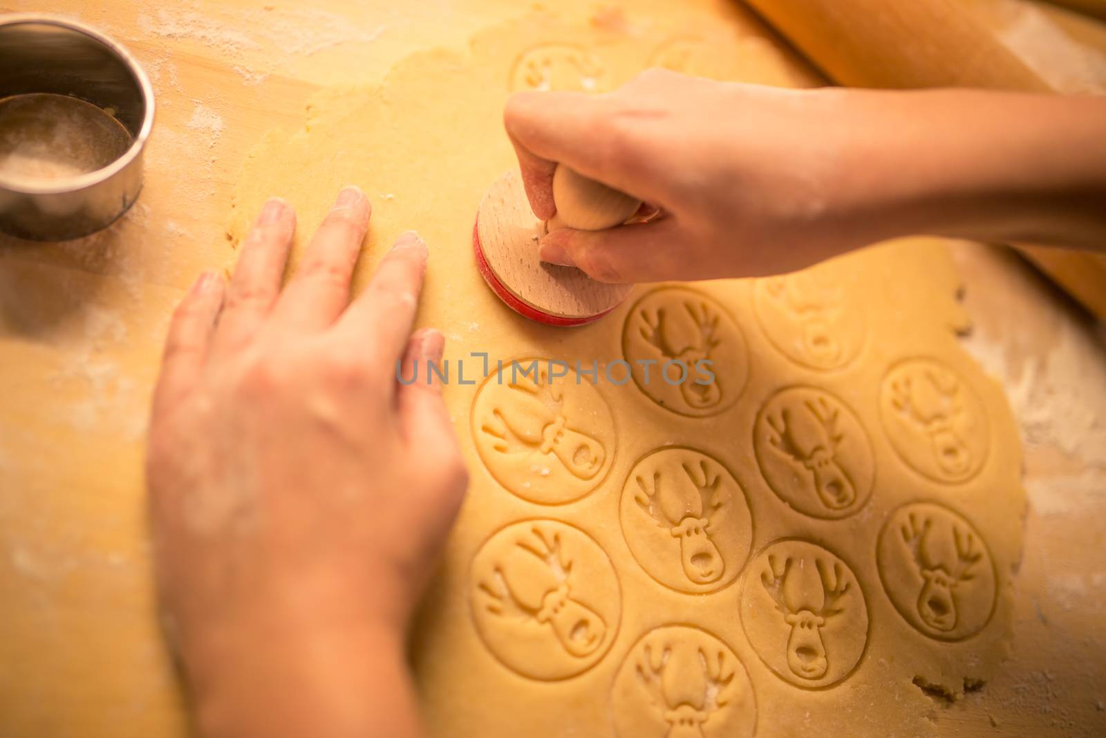 Womans's hand making traditional Christmas cookies. Raw dough and cutter for holiday cookies on the table. Prepare the gingerbread. Reindeer dough stamp. by petrsvoboda91