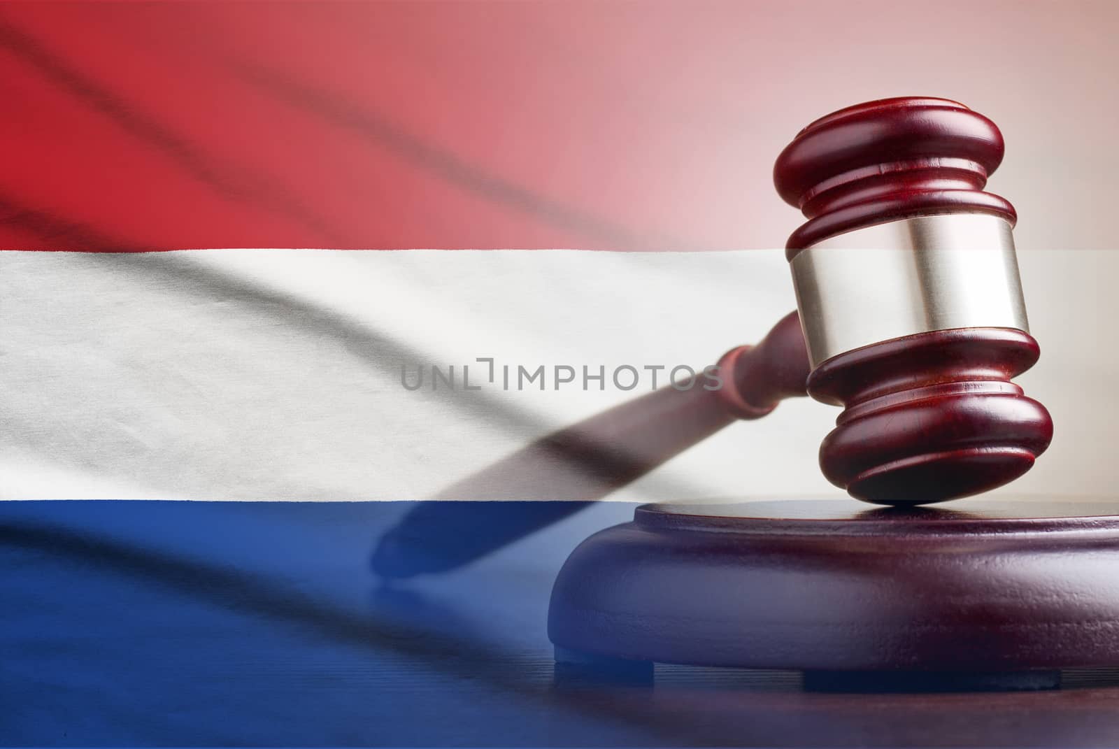 Legal gavel on its plinth over a flag of the Netherlands in a conceptual composite image