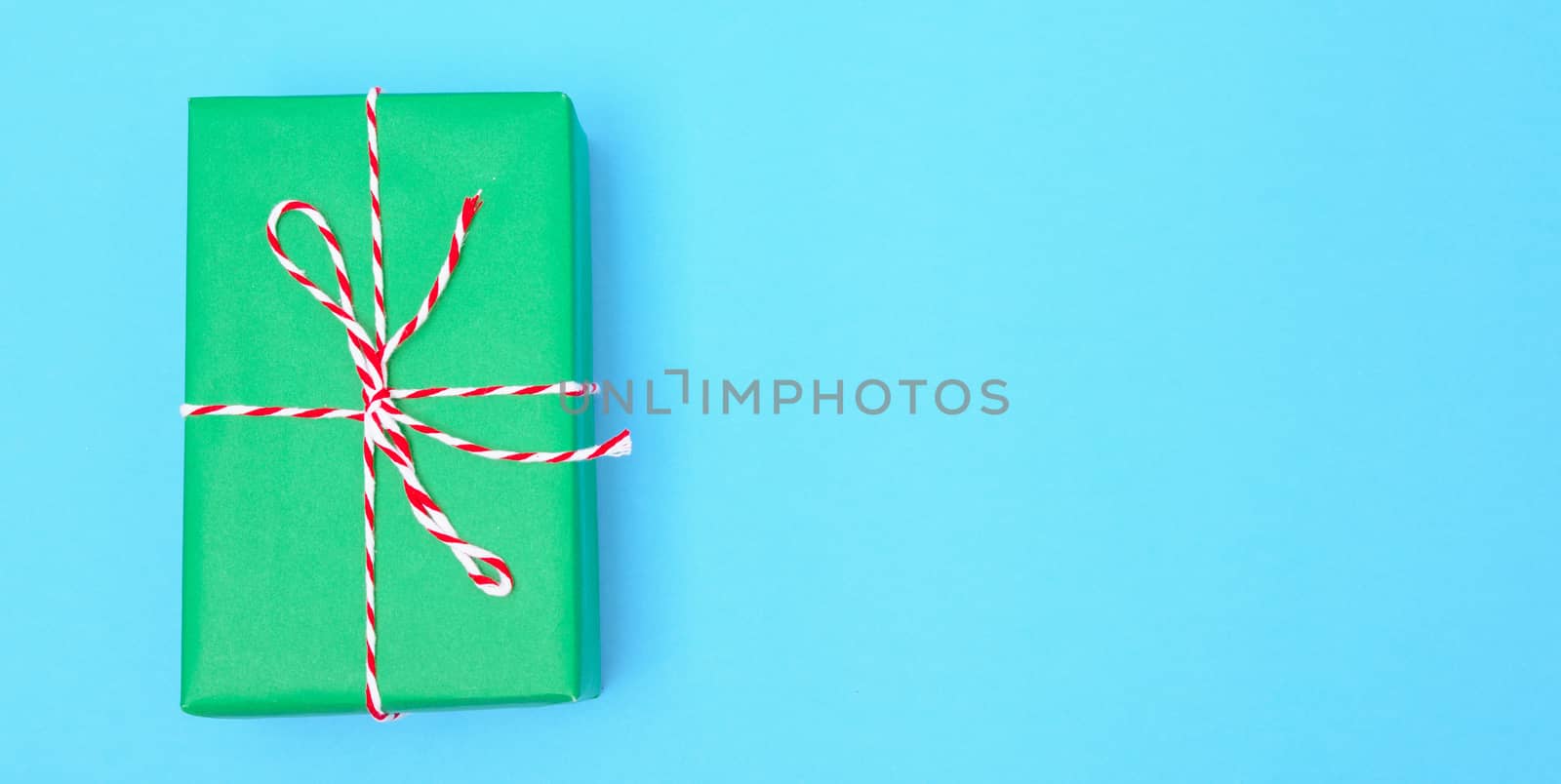 Happy New Year and Christmas 2020 or valentine day, top view craft paper wrapped present green gift box craft on blue background with copy space for your text