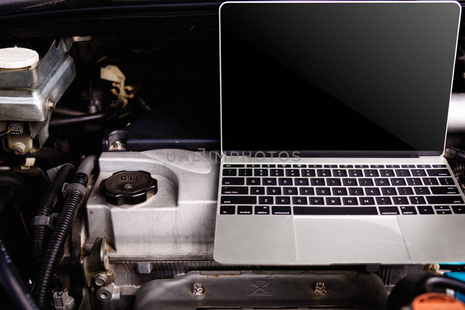 Laptop computer on car mechanic engine for service by Sorapop