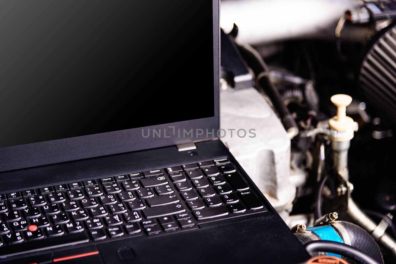 Laptop computer on car mechanic engine for service at workshop