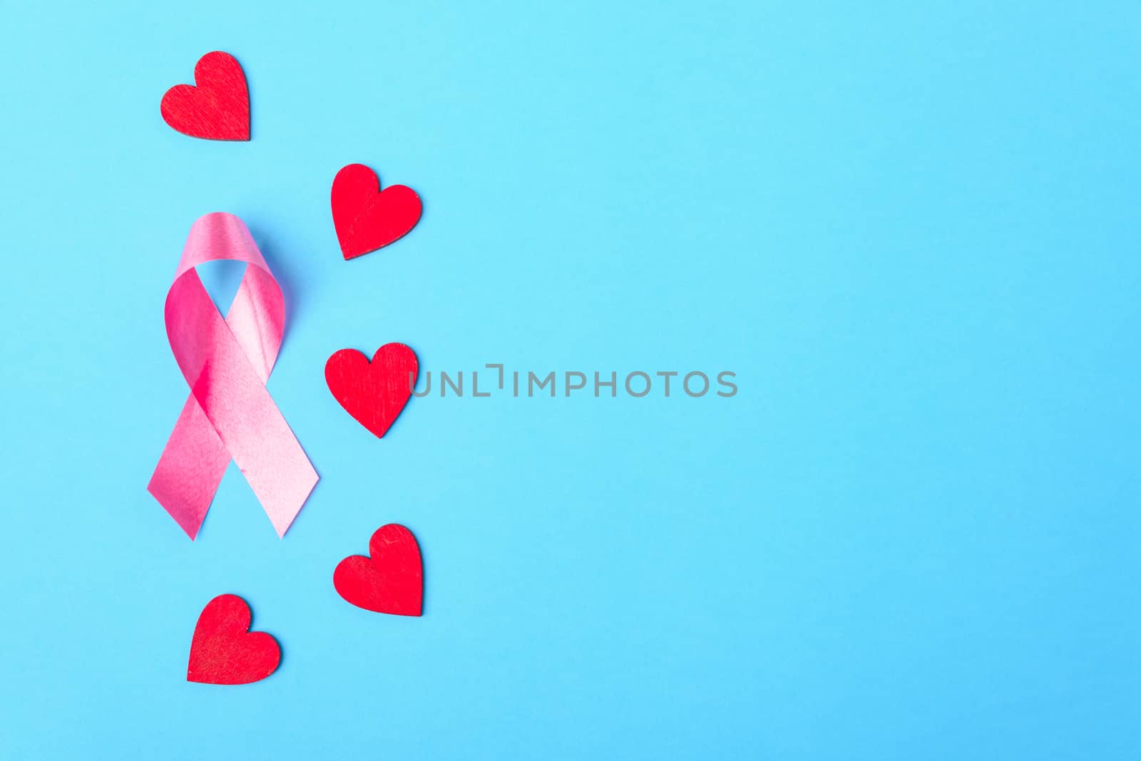 Breast cancer month concept, flat lay top view, pink ribbon and red Heart on blue background with copy space for your text