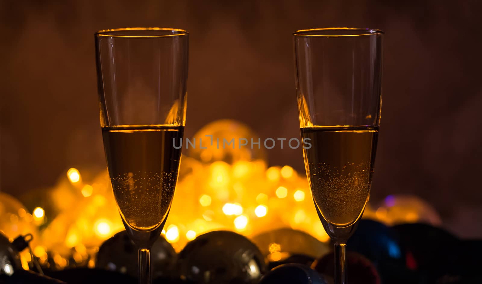 Glasses of champagne on the Christmas table with Christmas toys and garlands. New year and Christmas with glasses of champagne, holiday 2020.