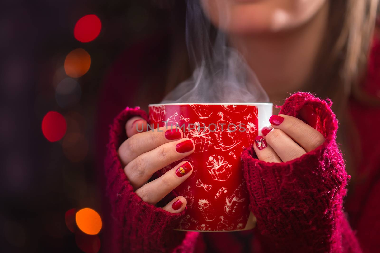 Detail of woman hands holding warm a cup of tea with steam. Blur Christmas background. Christmas or winter concept. by petrsvoboda91