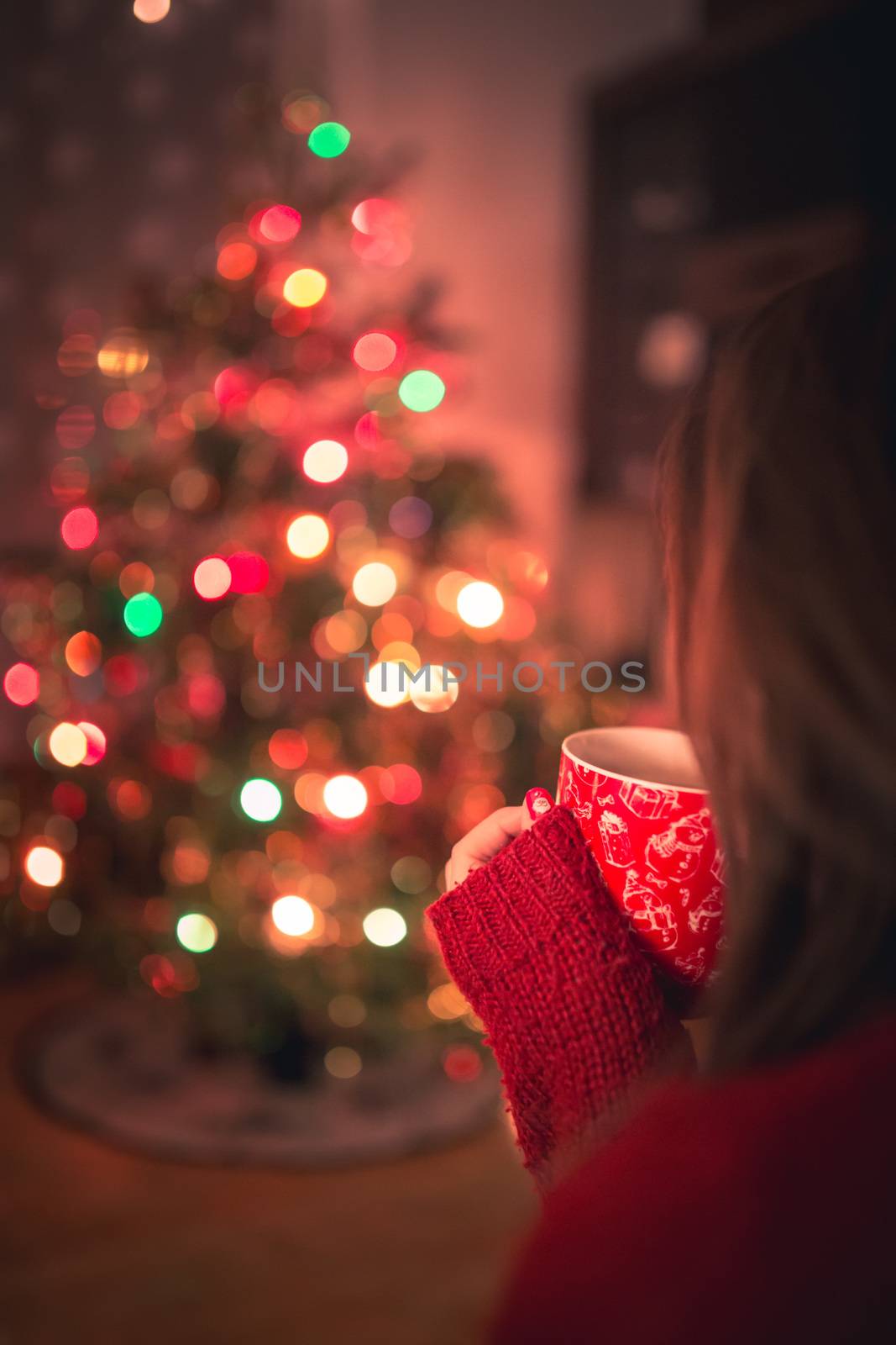 Young woman with cup of hot chocolate or tea or coffee in front of Christmas tree