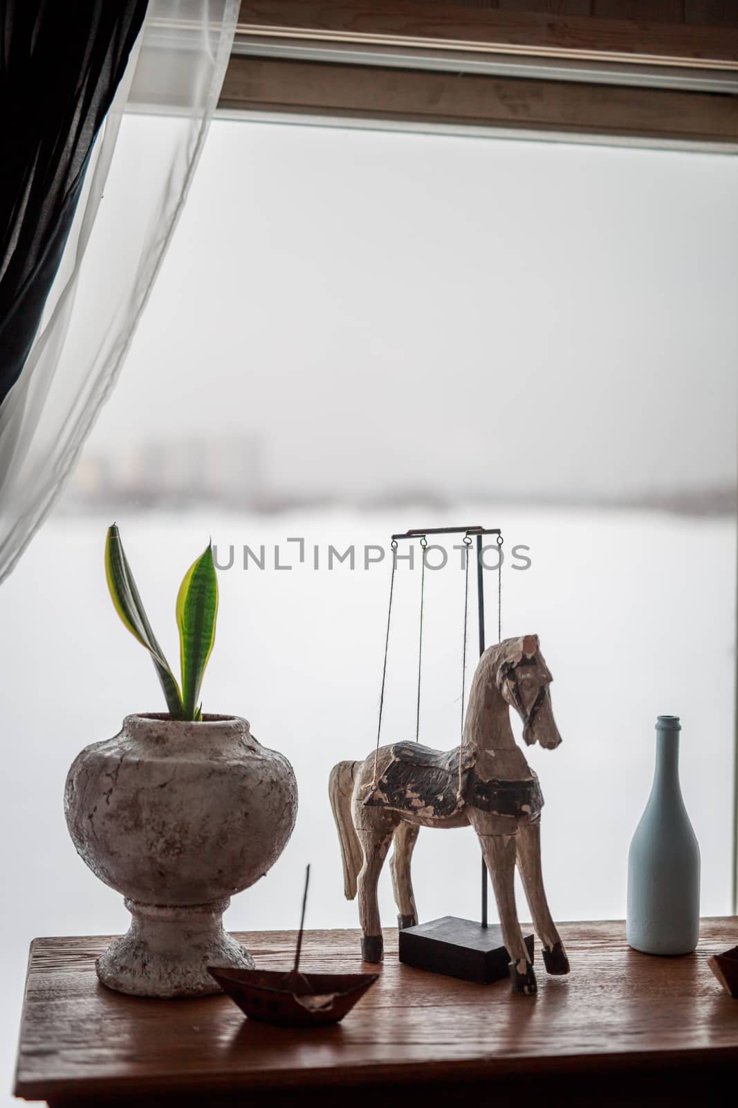 decorative wooden horse stands on the table near the window flowers in pots, white bottle, iron boat, elements of room decoration, decor, Provence, delicate tones by dikkens