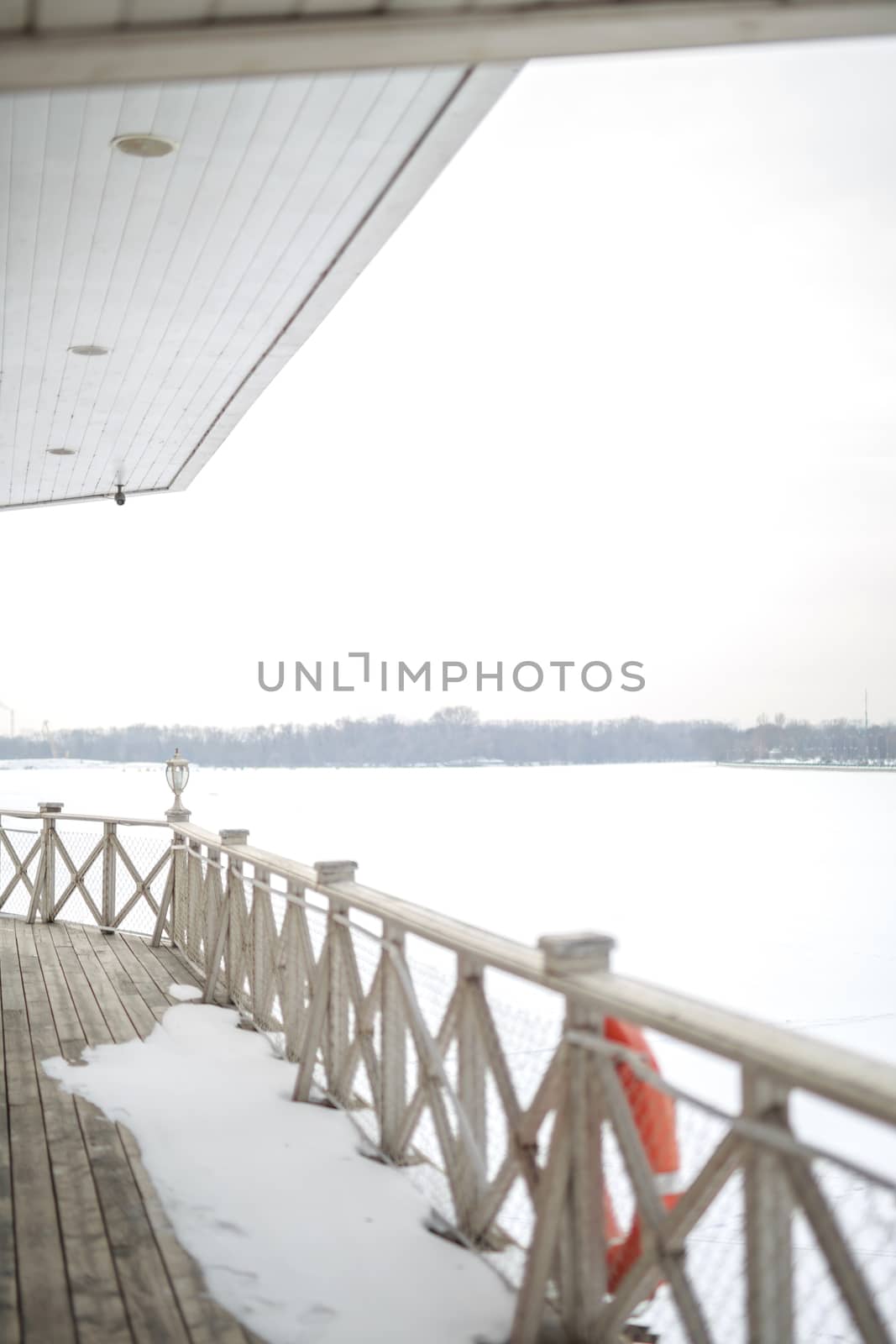 white snow on the wooden vintage open deck, old peeling paint light milk color, steel and copper lanterns hanging on the wall, snowy winter, snow lies on the river and the far shore of the earth is vi by dikkens