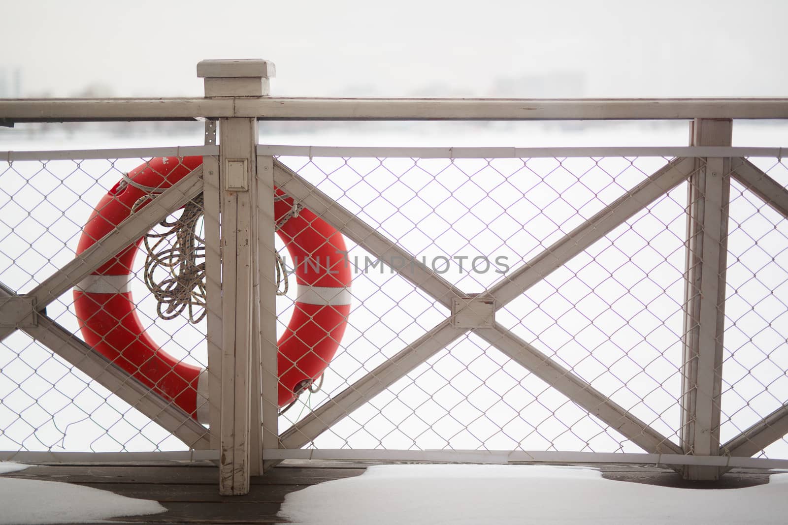 lifebuoy hanging on the wooden fence of the ship standing in the winter on the pier, a view of the winter surface of the river by dikkens