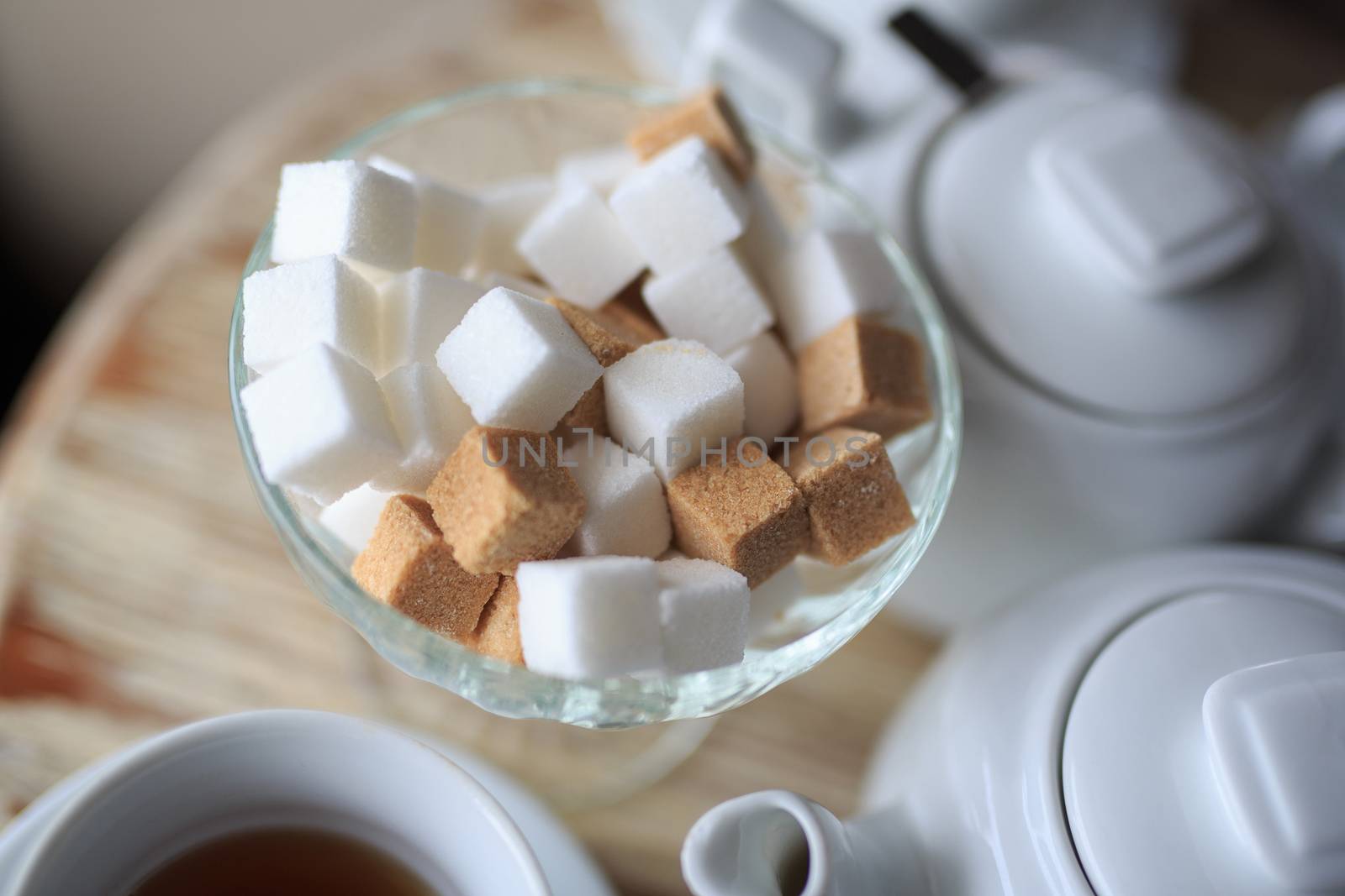 morning Cup of tea stands on the edge of the wooden Desk, square pieces of sugar in the sugar bowl, tea kettle, coffee kettle