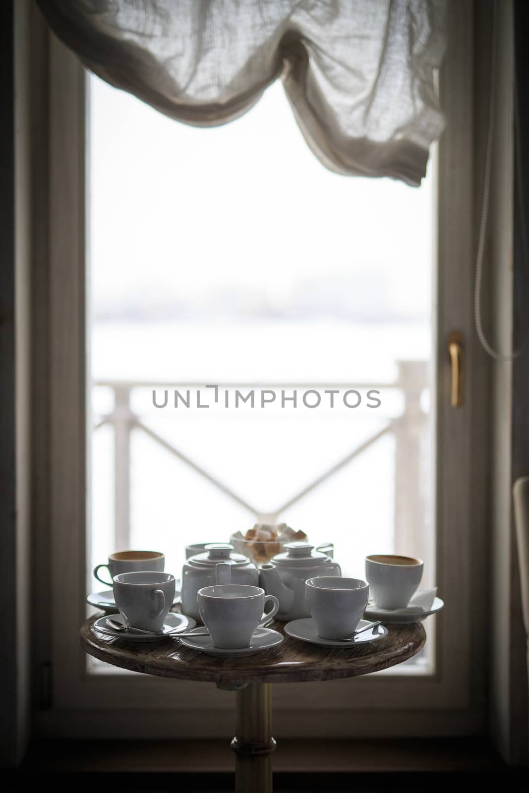 a white tea service stands at the window on a table in a cafe, without people, sugar in a sugar bowl by dikkens