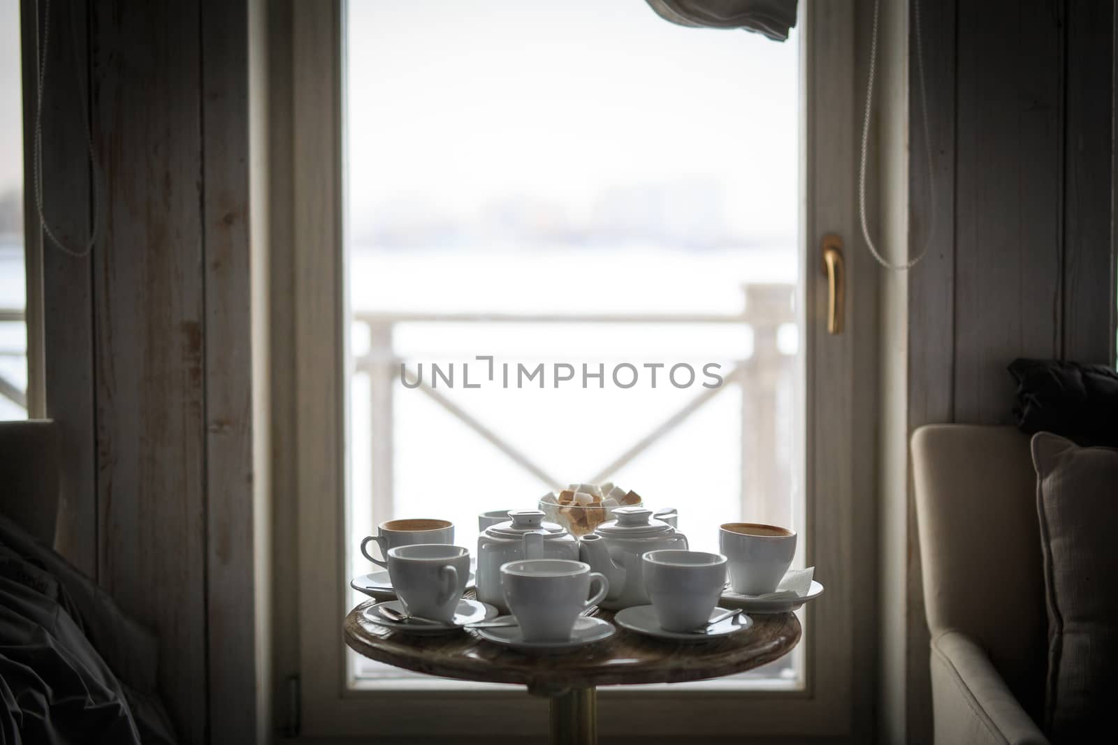 a white tea service stands at the window on a table in a cafe, without people, sugar in a sugar bowl by dikkens