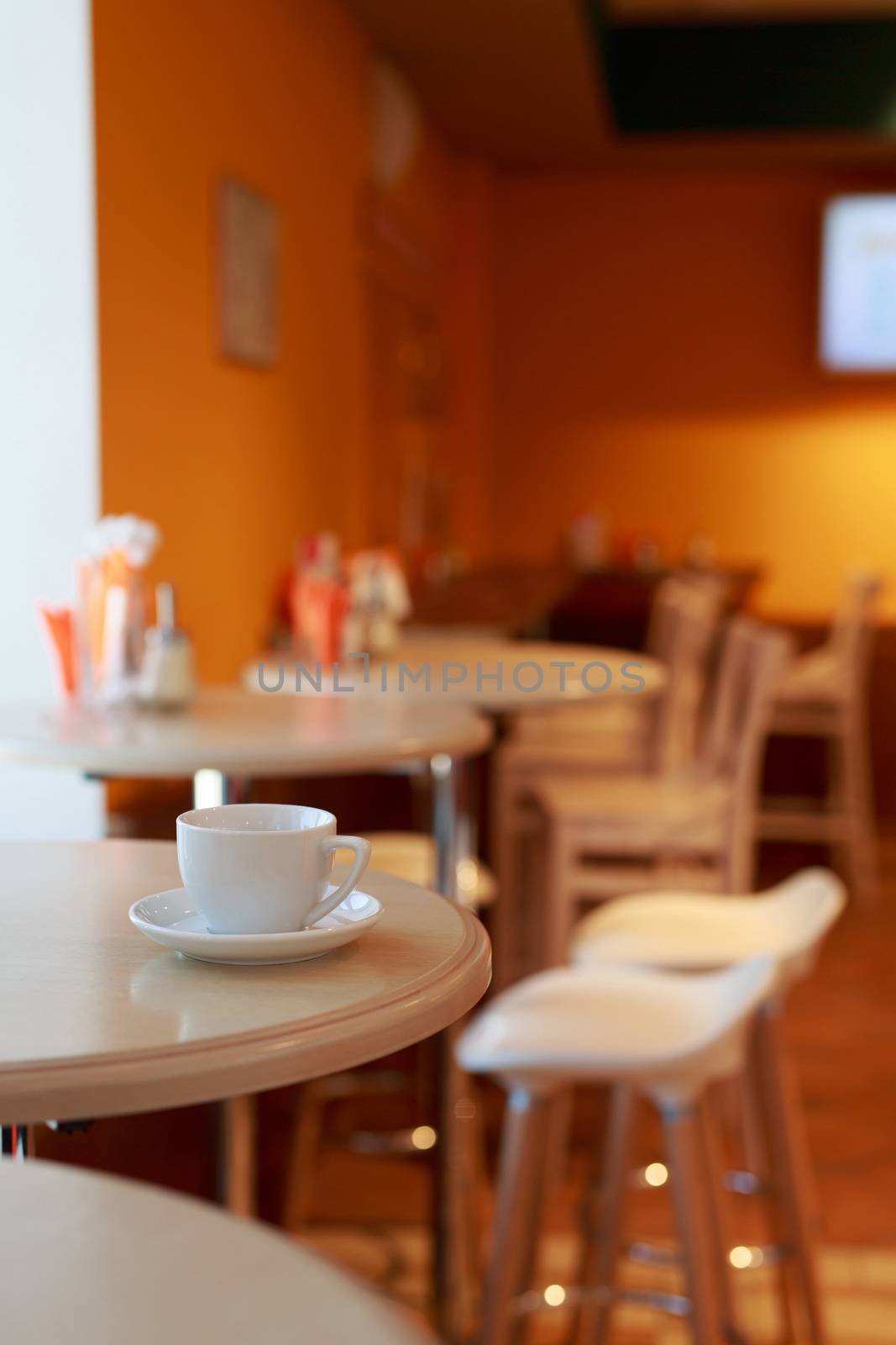 coffee Cup is on the table in a cafe with a blurry background , white tea Cup, Breakfast, cafe background orange by dikkens