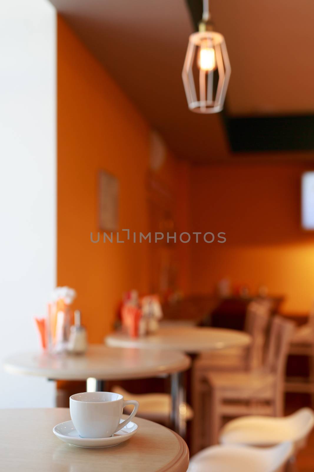 coffee Cup is on the table in a cafe with a blurry background , white tea Cup, Breakfast, cafe background orange by dikkens