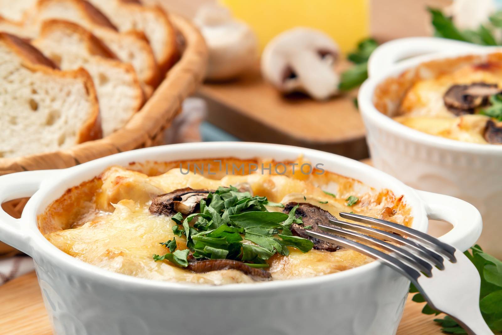 Casserole with chicken, mushrooms and cheese, known in Russia as julienne in white bowls with herbs, close up by galsand