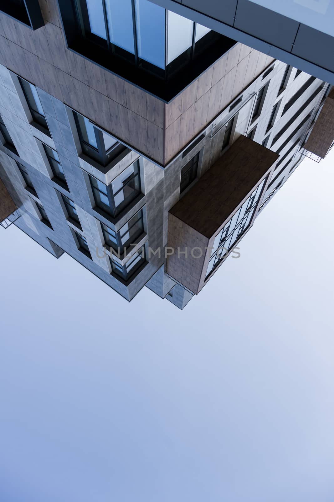 Conceptual flipped geometric street photo of business building. Soft blue sky without clouds.