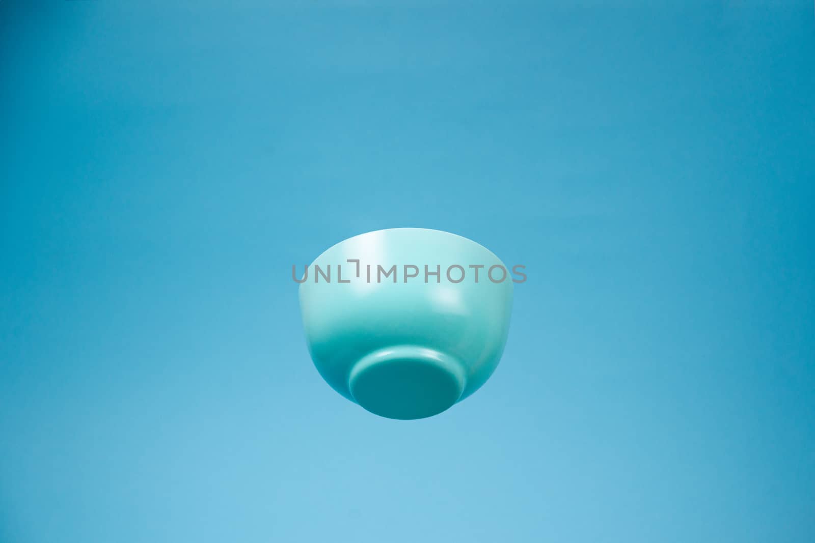 A blue ceramic mattle deep bowl for breakfast flying on blue background. Ideal photo for levitation of food and fruits or nuts.