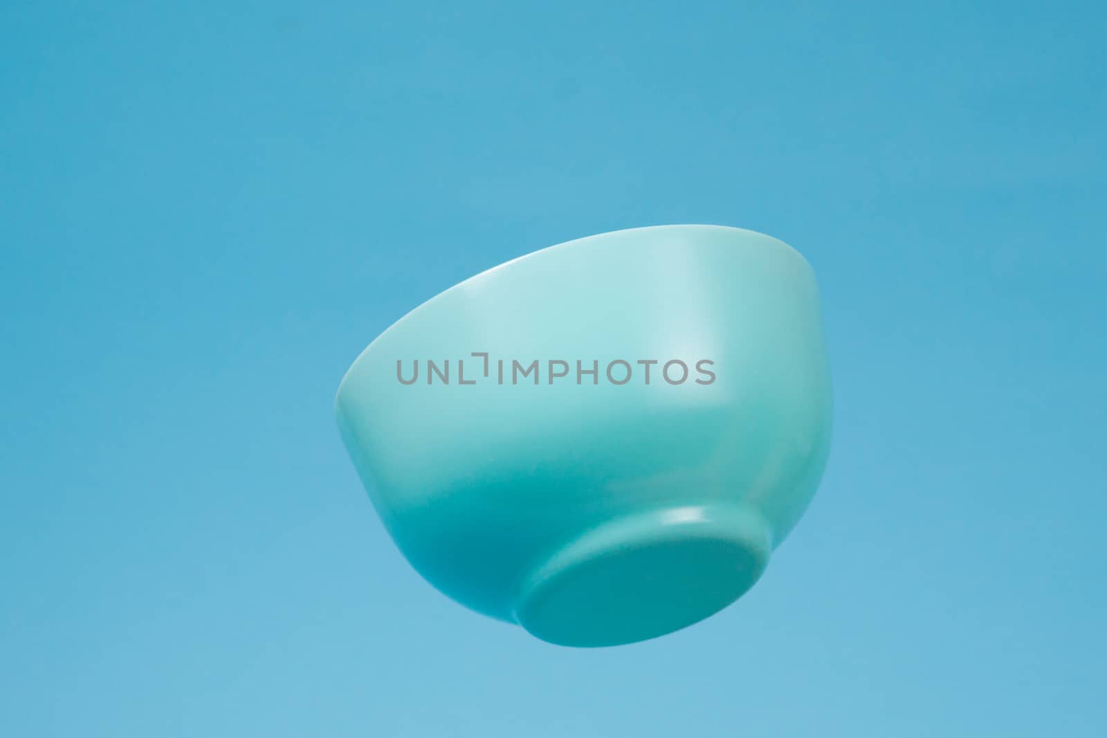 A blue ceramic mattle deep bowl for breakfast flying on blue bac by alexsdriver